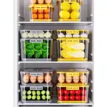 Clear plastic pantry storage containers with colorful fruits and vegetables.