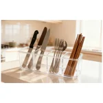 Transparent plastic cutlery organizer with knives, forks, and chopsticks.